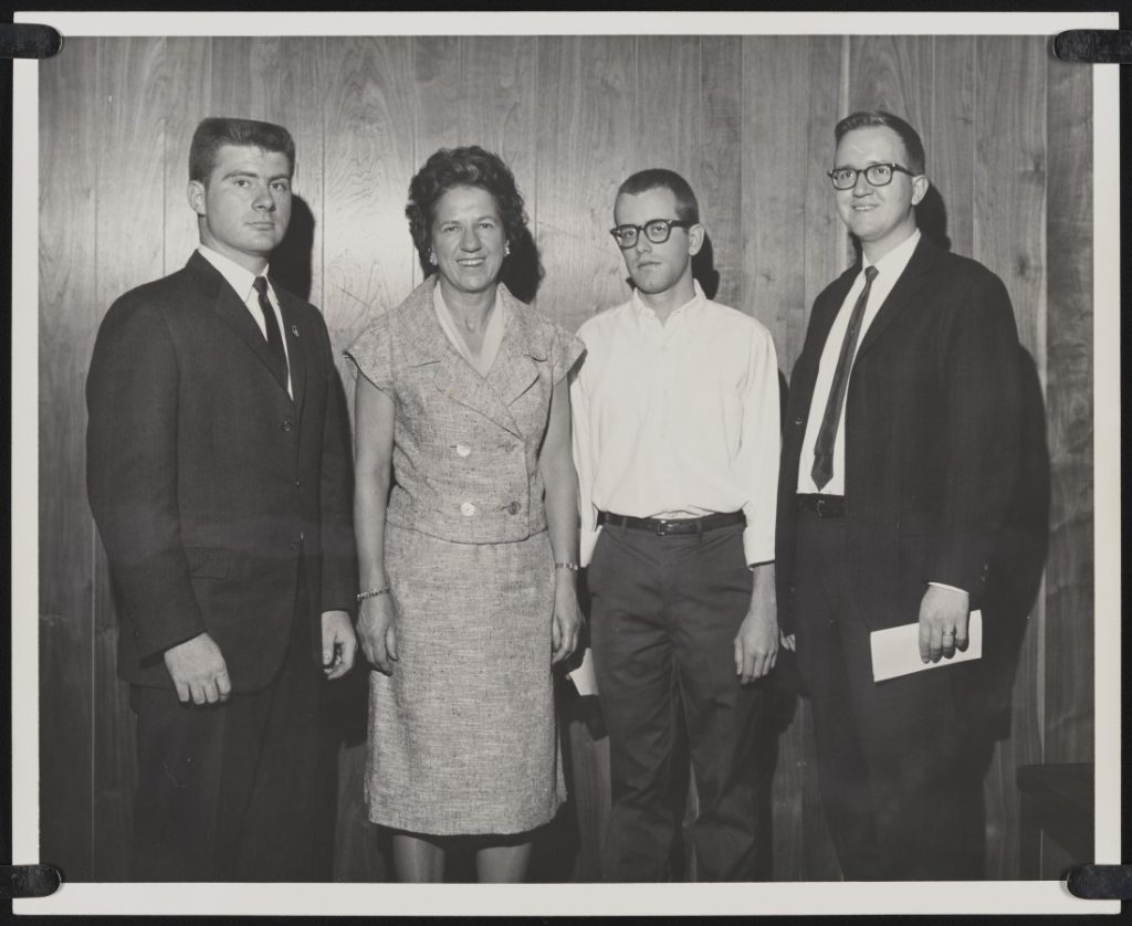 Black-and-white photograph of three young men and an older woman.