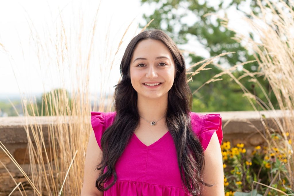 Headshot photograph of a woman in a bright pink top.