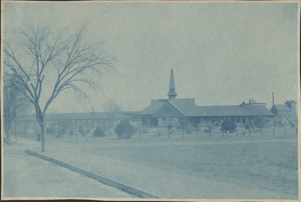 Blue-tinted photograph of a large one-story building with a prominent steeple.