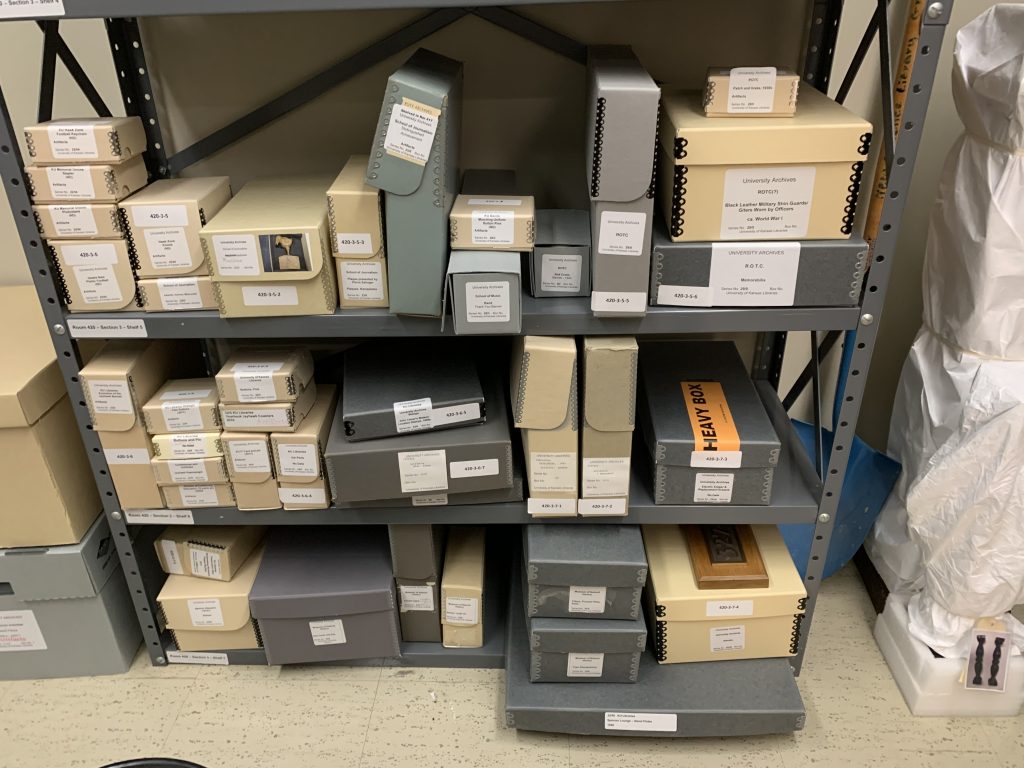 Archival artifact storage is pictured before inventory and rehousing, with many disparate sizes and shapes of boxes.
