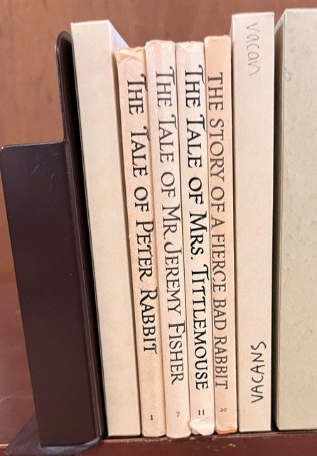 Color photograph of four Beatrix Potter books lined up vertically.