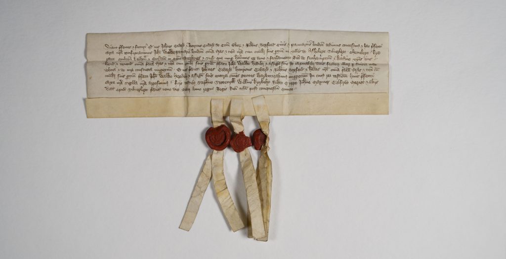 Parchment document with three parchment strips attached, each of which has a red wax seal.
