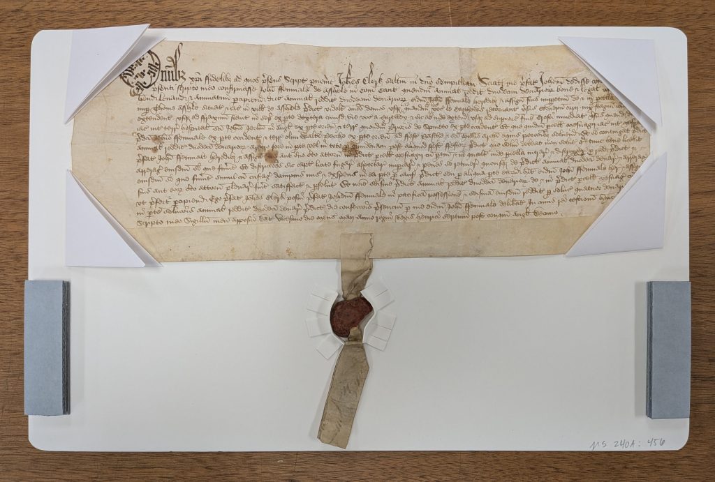 Parchment document mounted on a piece of matboard, with support around the small, wax, pendent seal.