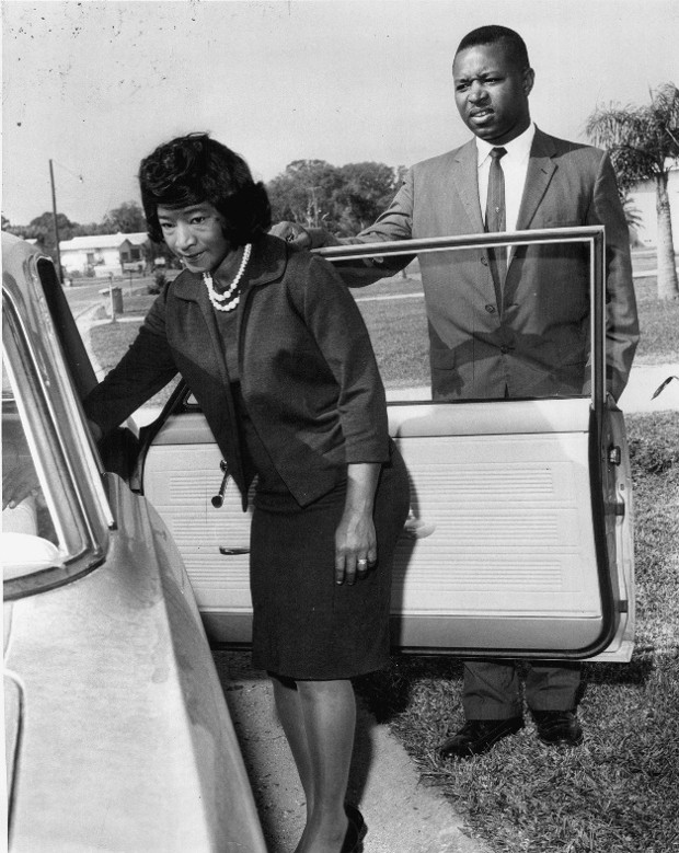 Photograph of Elenora Adams entering a car, with Sam Adams standing behind her behind the car door.